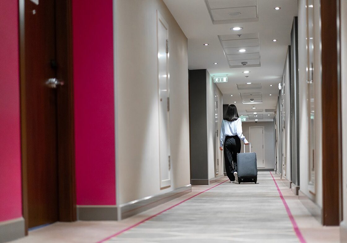 A girl with a suitcase walks down the hotel corridor rear view of a business woman during trip