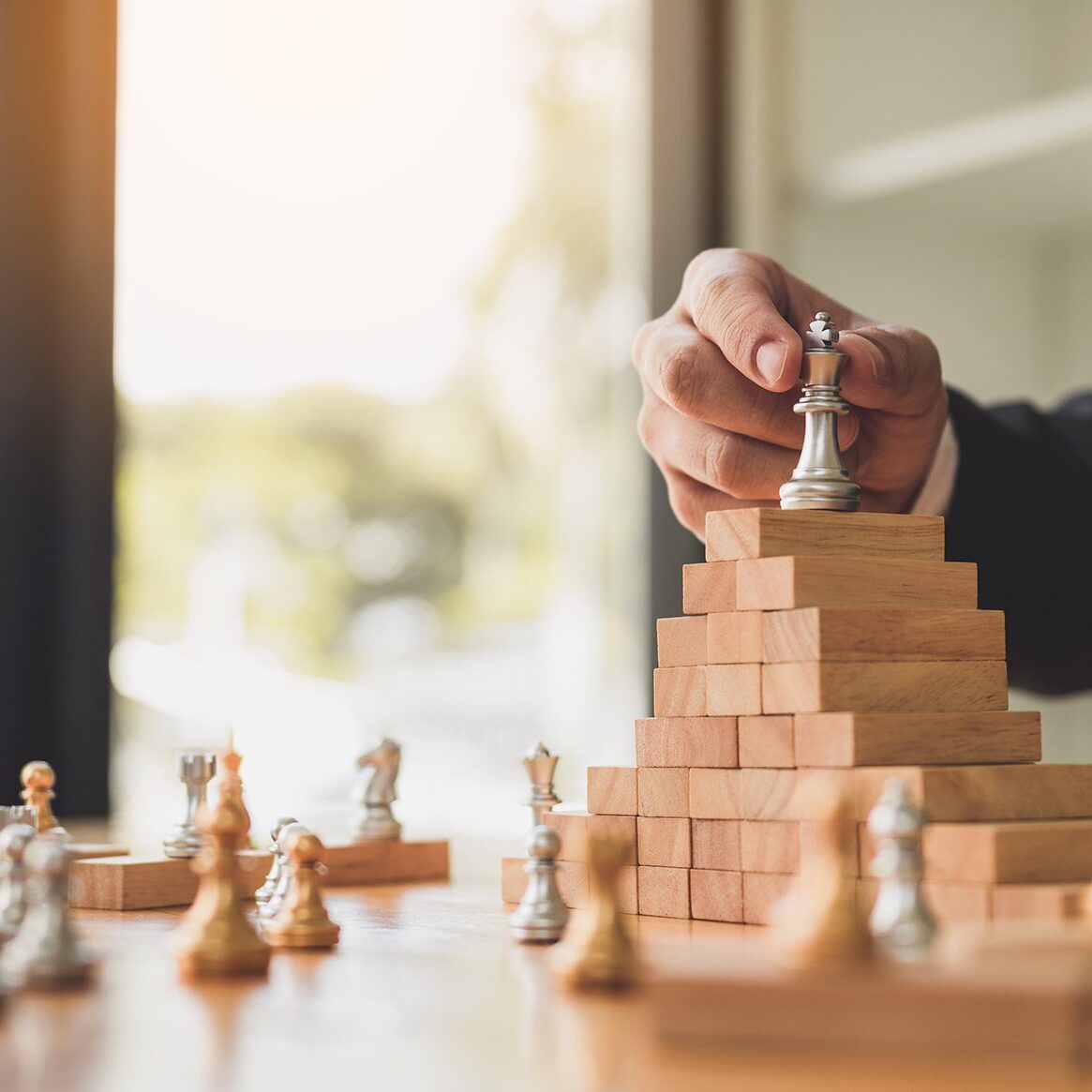 Businessman hand picking chess on top block wood about leadership concept.